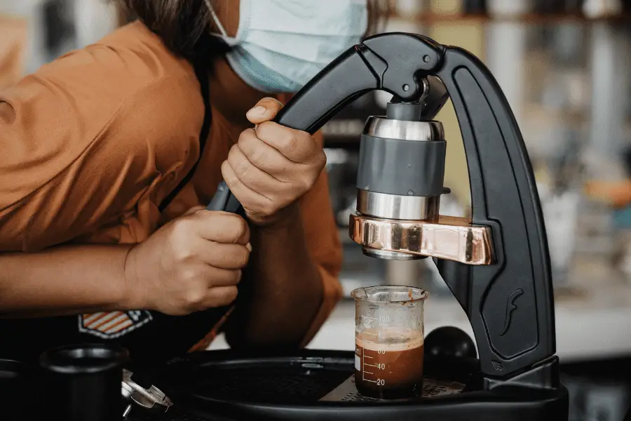 Woman pushing the lever of a Flair espresso maker.